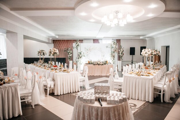 Sala da banchetto bianca per matrimoni con tavoli rotondi decorati con fiori freschi