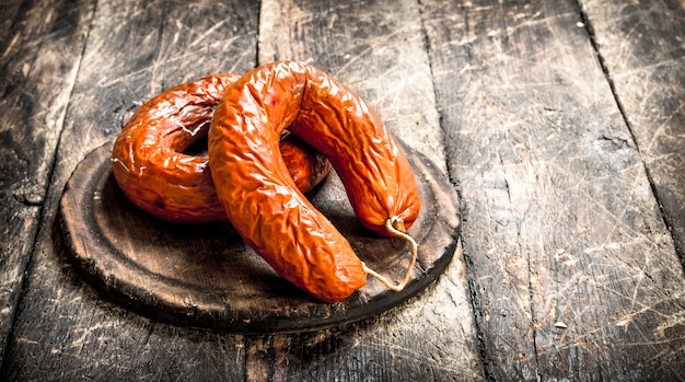 Salame affumicato con spezie e aglio. Su uno sfondo di legno.