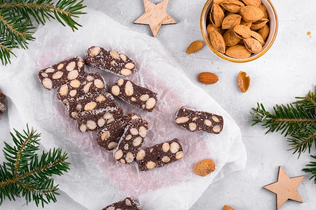 Salame al cioccolato affettato con mandorle su un dolce di Natale in carta da forno