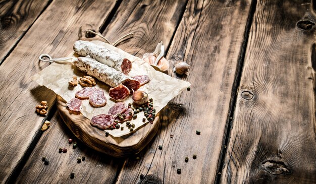 Salame aromatizzato con aglio e spezie su un tavolo di legno.