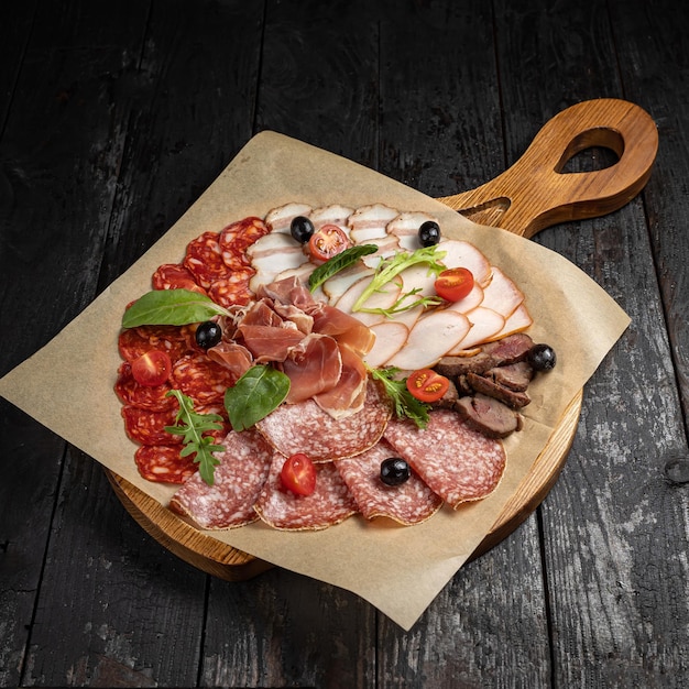 salame con salsiccia, prosciutto, pomodori, olive e basilico su tavola di legno