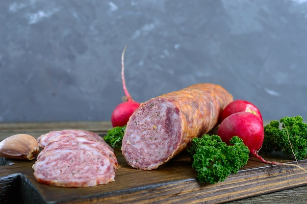 Salame di salsiccia kraft fatto in casa, affettato su una tavola di legno.