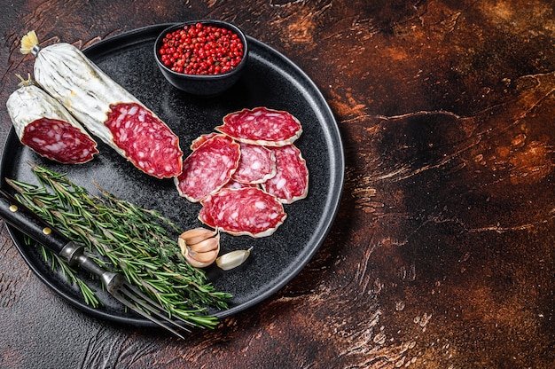 Salame italiano a fette su un piatto con rosmarino e timo