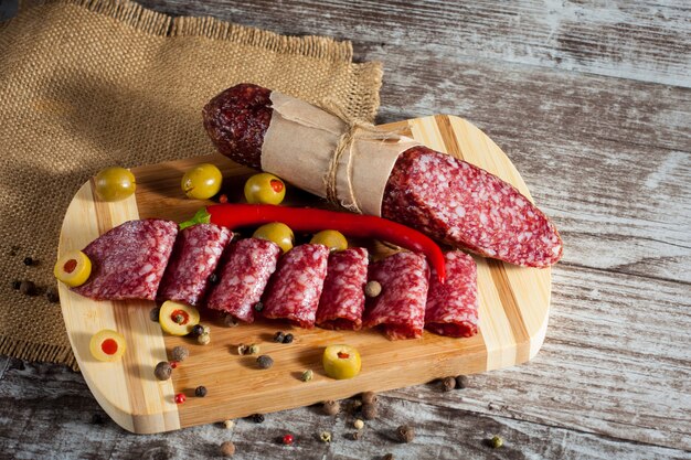 Salame italiano con olive e spezie su fondo in legno