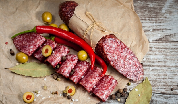 Salame italiano con olive e spezie su fondo in legno