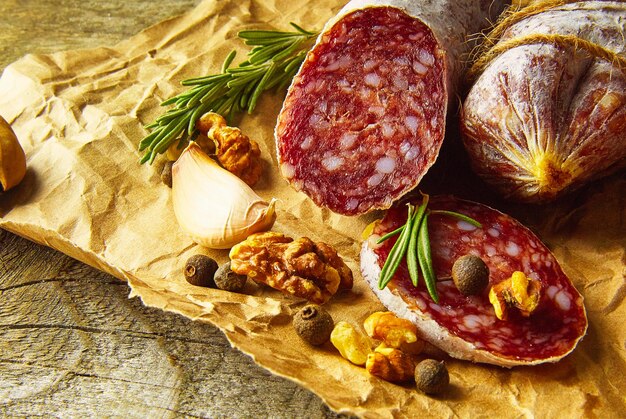 Salame italiano con sale marino, rosmarino, aglio e noci su carta, in stile rustico, vista dall'alto