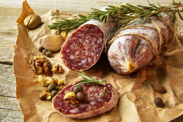 Salame italiano con sale marino, rosmarino, aglio e noci su carta. Stile rustico Primo piano