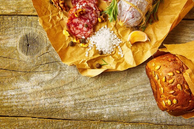 Salame italiano con sale marino, rosmarino, aglio e noci su carta. Stile rustico Primo piano