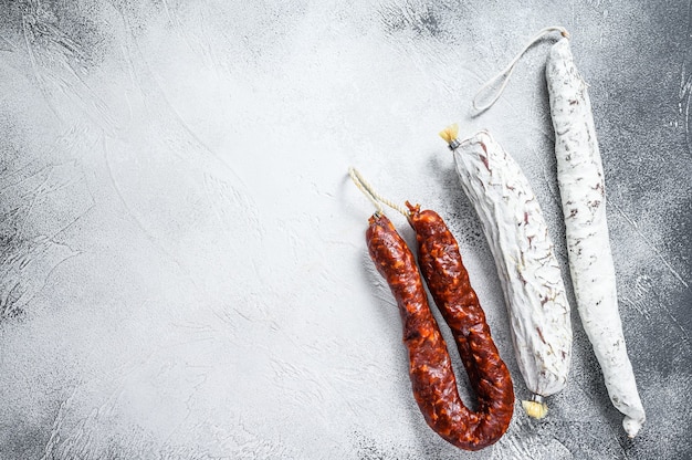 Salame spagnolo, fuet e chorizo su un tavolo da cucina. Sfondo bianco. Vista dall'alto. Copia spazio.