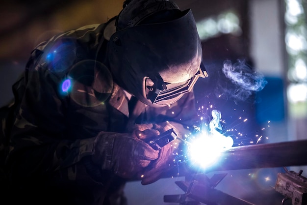 Saldatore al lavoro Uomo con maschera protettiva Il saldatore esegue cuciture sul metallo