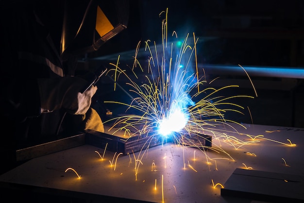 Saldatore di metalli che lavora con saldatrice ad arco per saldare l'acciaio in fabbrica.