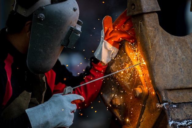 Saldatore in maschera di ferro casco salda con saldatura ad arco elettrico in acciaio Operaio industriale in fabbrica