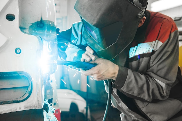 Saldatore in maschera protettiva salda carrozzeria Veicolo per la lavorazione dei metalli con saldatrice ad anidride carbonica