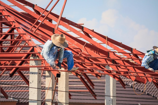 Saldatori edili che installano la struttura del telaio in acciaio del tetto della casa