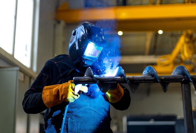 Saldatura di lavoratori in metallo in fabbrica Specialista della saldatura che lavora con maschera protettiva