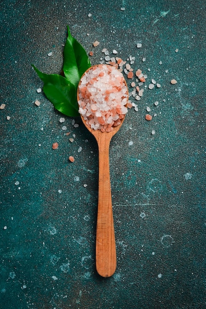 Sale grosso rosa da cucina marina in un cucchiaio di legno su uno sfondo scuro con texture