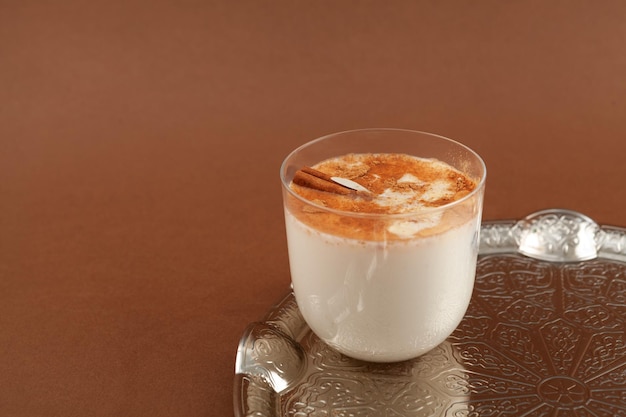 Salep o Sahlep in vetro su sfondo marrone Salep Turkish drink istantaneo con cannella