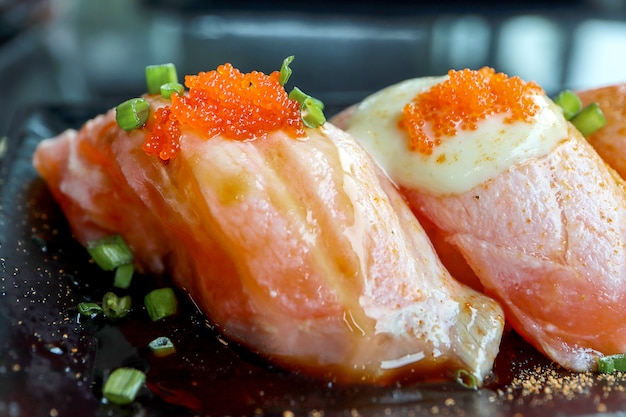 Salmon Sushi con le uova di tobiko sulla cima in banda nera.