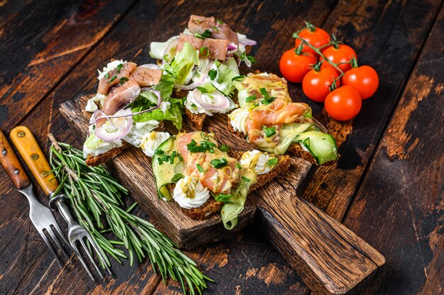 Salmone affumicato e panino alle aringhe con crema di formaggio e insalata su un tagliere.