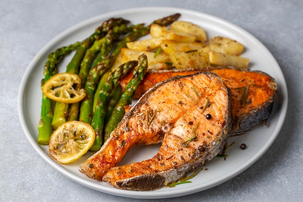 Salmone al forno alla griglia servito su un piatto con asparagi e patate