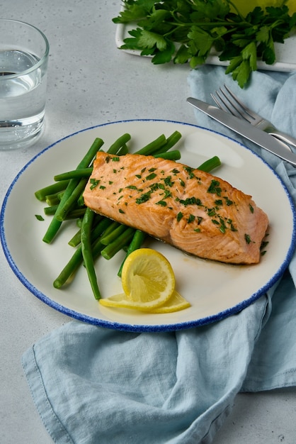 Salmone al forno con asparagi fetta di limone olio di prezzemolo e bicchiere d'acqua cibo dietetico sano