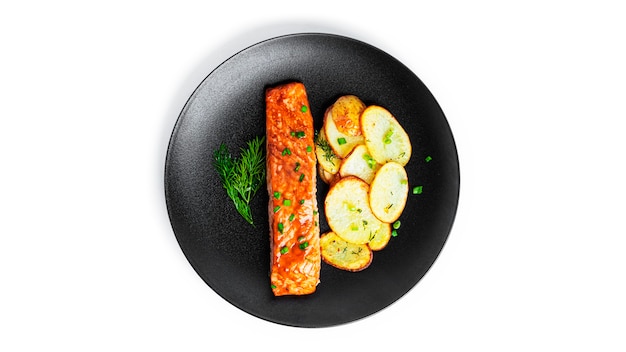 Salmone al forno e patate con erbe aromatiche isolate su bianco.