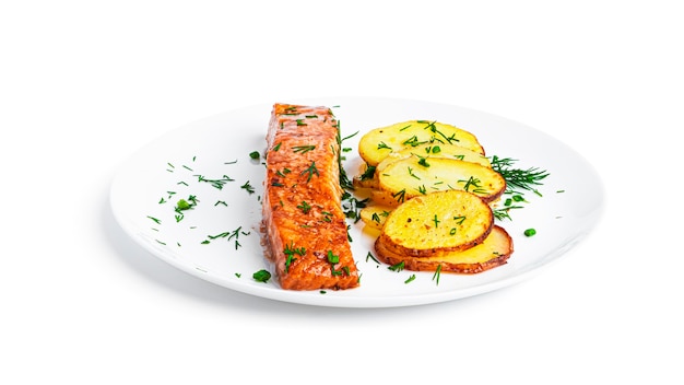 Salmone al forno e patate con erbe su piatto bianco isolato