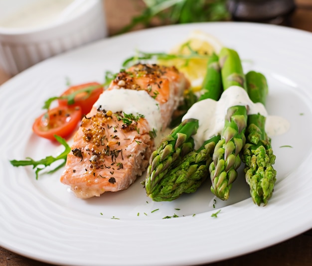 Salmone al forno guarnito con asparagi e pomodori con erbe