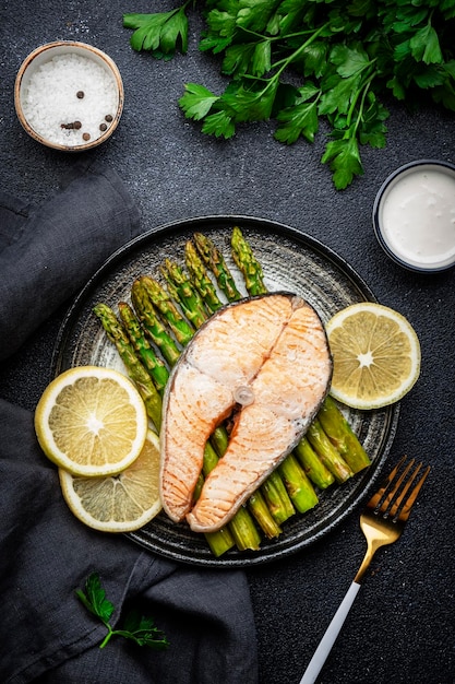 Salmone al vapore al forno con asparagi e limone con salsa olandese su piatto Vista dall'alto dello sfondo del tavolo nero