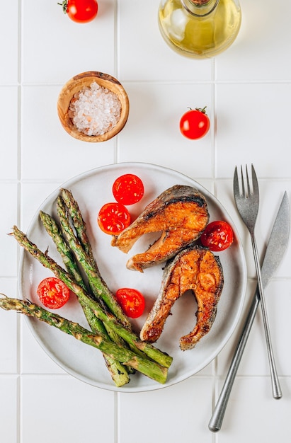 Salmone alla griglia con asparagi su uno sfondo bianco a piastrelle concetto di dieta mediterranea