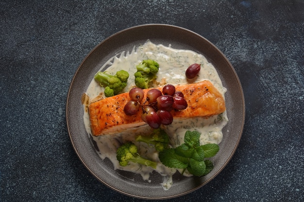 Salmone alla griglia con uva rossa arrosto e broccoli in salsa cremosa all'aglio