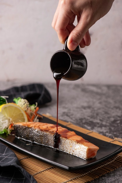 Salmone alla griglia, semi di sesamo e maggiorana su un piatto nero. Colpo dello studio