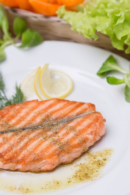 Salmone arrostito caldo con il contorno sul piatto bianco