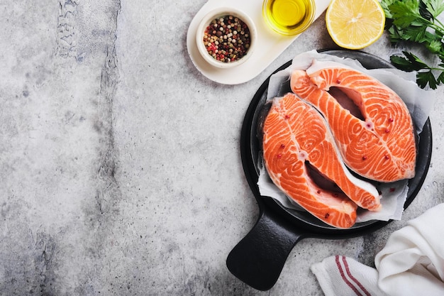 Salmone Bistecca di salmone crudo Pesce salmone crudo fresco con ingredienti da cucina erbe e limone preparato per la cottura alla griglia su sfondo grigio chiaro Cibo sano Vista dall'alto Spazio di copia