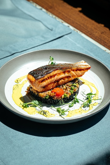 Salmone con salsa cremosa al basilico e riso nero