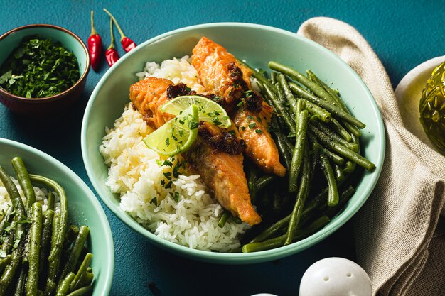 Salmone fresco fritto con zenzero e aglio nel latte di cocco, con riso basmati e fagiolini nei piatti sul tavolo. ricetta salutare per tutta la famiglia.