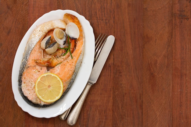 Salmone fritto con frutti di mare e limone sul piatto bianco