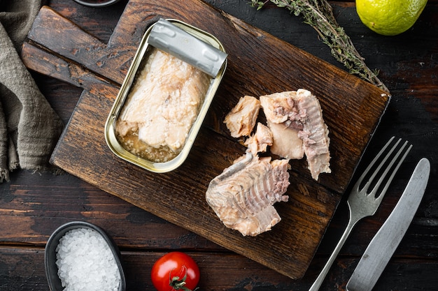 Salmone in scatola, conserve di pesce, su tagliere di legno, su un vecchio tavolo di legno scuro