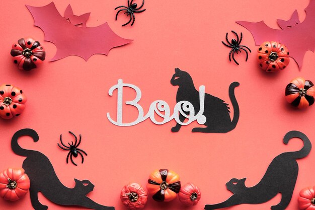 Salmone rosa arancione Sfondo di Halloween Sagome di gatti neri pipistrelli di carta e ragni neri Zucche deco decorative rosa con strisce e pois Testo piatto Boo