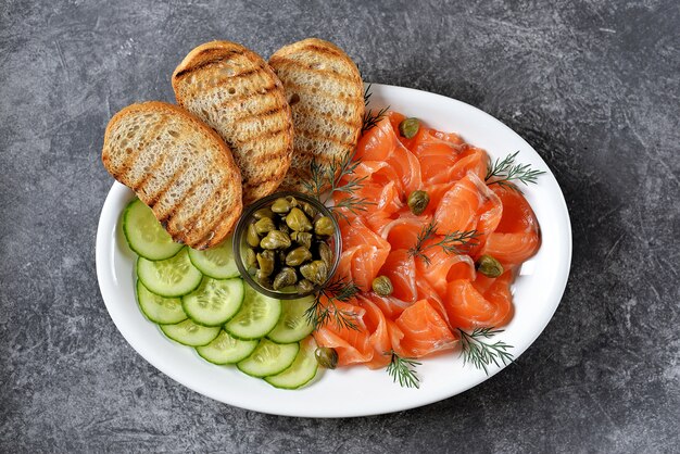 Salmone salato, cetriolo, capperi, aneto e pane grigliato