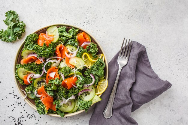 Salmone salato (trota) e insalata di cavolo in un piatto bianco su uno sfondo bianco, vista dall&#39;alto.