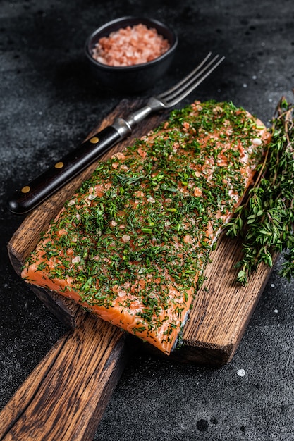 Salmone stagionato Gravlax con aneto e sale su tavola di legno