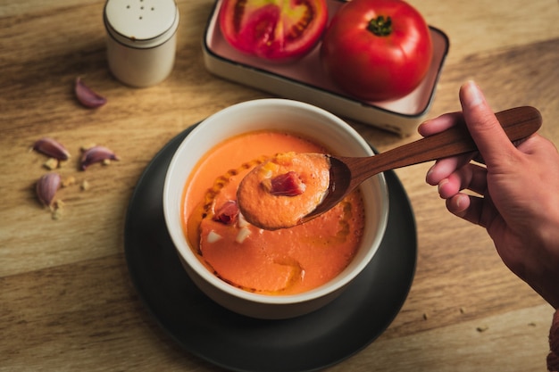 Salmorejo su piatto con cucchiaio e tavolo in legno