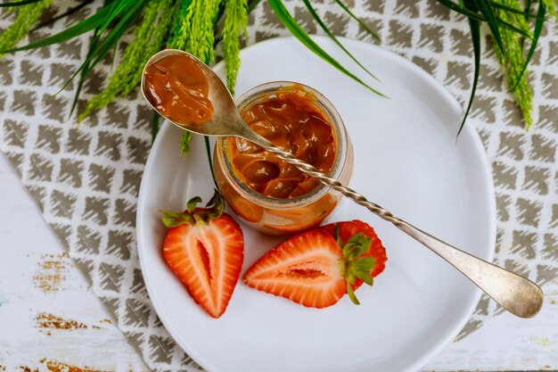 Salsa al caramello in un barattolo di vetro con fragole a fette.