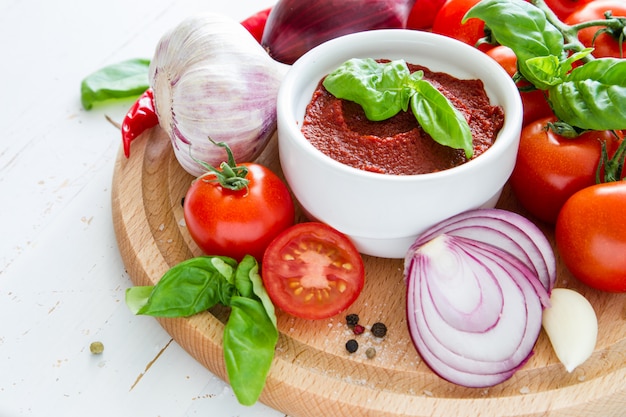 Salsa al pomodoro e ingredienti su fondo di legno bianco