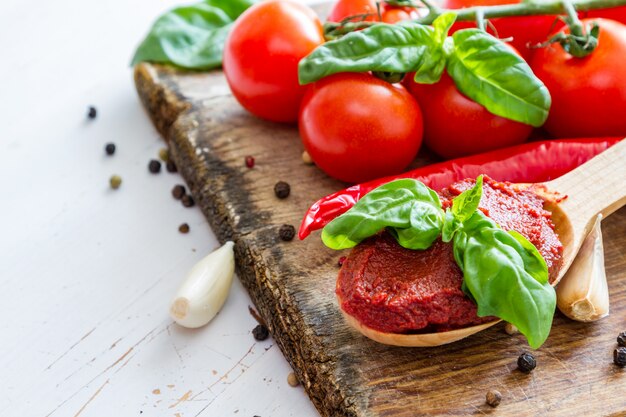 Salsa al pomodoro e ingredienti su fondo di legno bianco