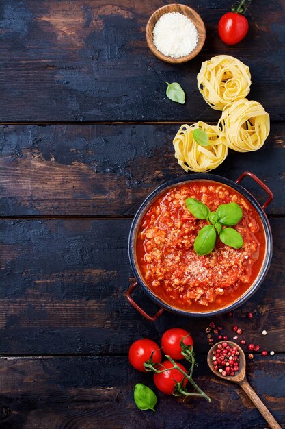 Salsa bolognese italiana tradizionale in casseruola un vecchio tavolo di legno scuro. Vista dall'alto