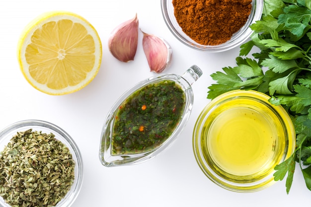 Salsa Chimichurri verde ed ingredienti isolati sulla vista superiore di superficie bianca