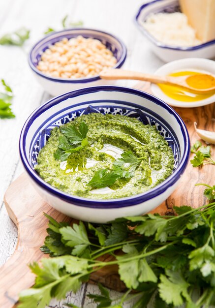 Salsa di pesto e ingredienti fatti in casa del prezzemolo su legno bianco