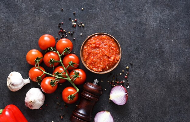 Salsa di pomodoro con pepe e aglio su uno sfondo scuro di cemento.